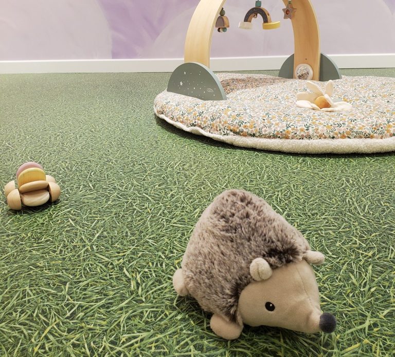 Espace bébé avec tapis sensoriel et jeux doux favorisant l’éveil et la motricité en toute sécurité.